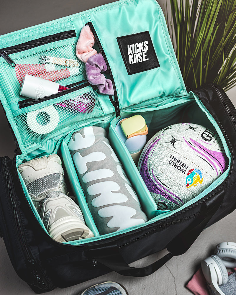 Teal KICKS KASE organizer with shoes, socks, and a soccer ball inside a suitcase.