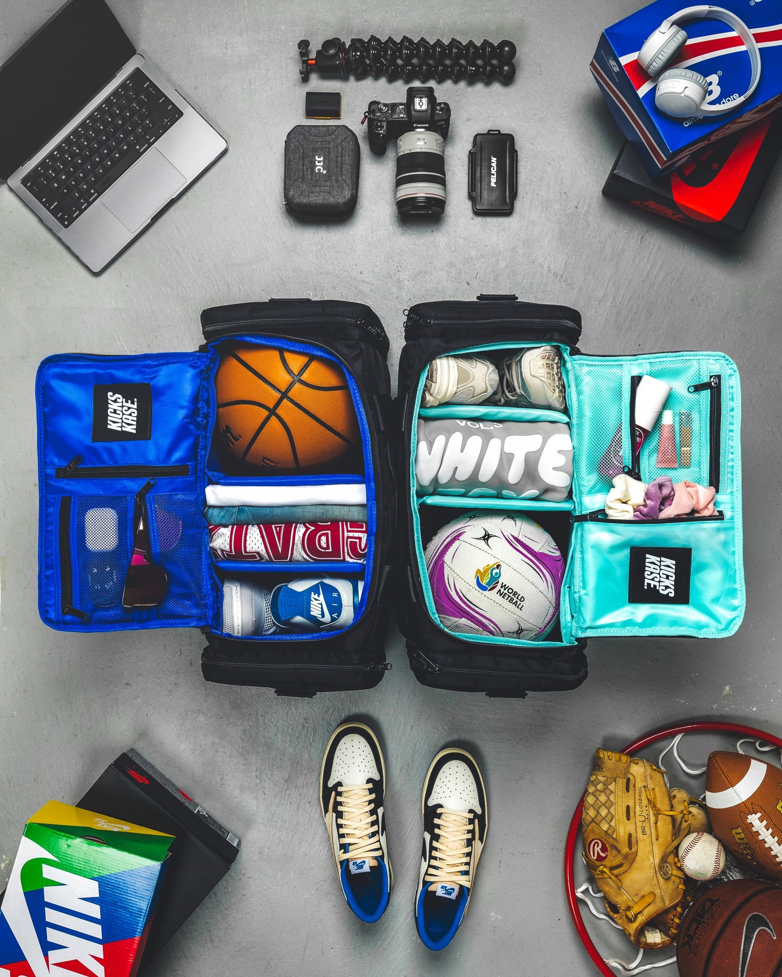 Open travel bag with sports equipment and personal items for basketball and netball on a gray surface